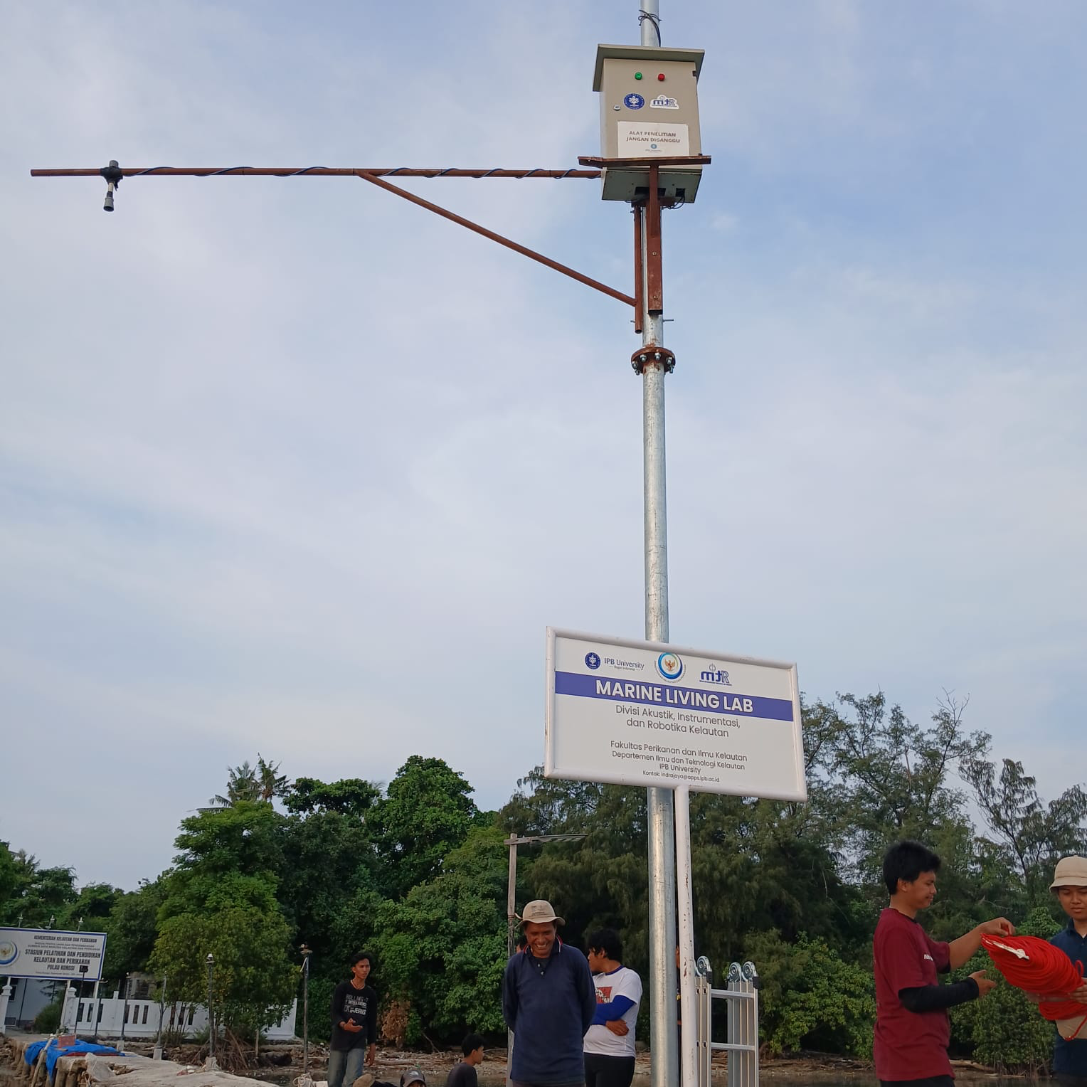 Papan nama Marine Living Lab dan lengan sensor angin di dermaga Pulau Pari